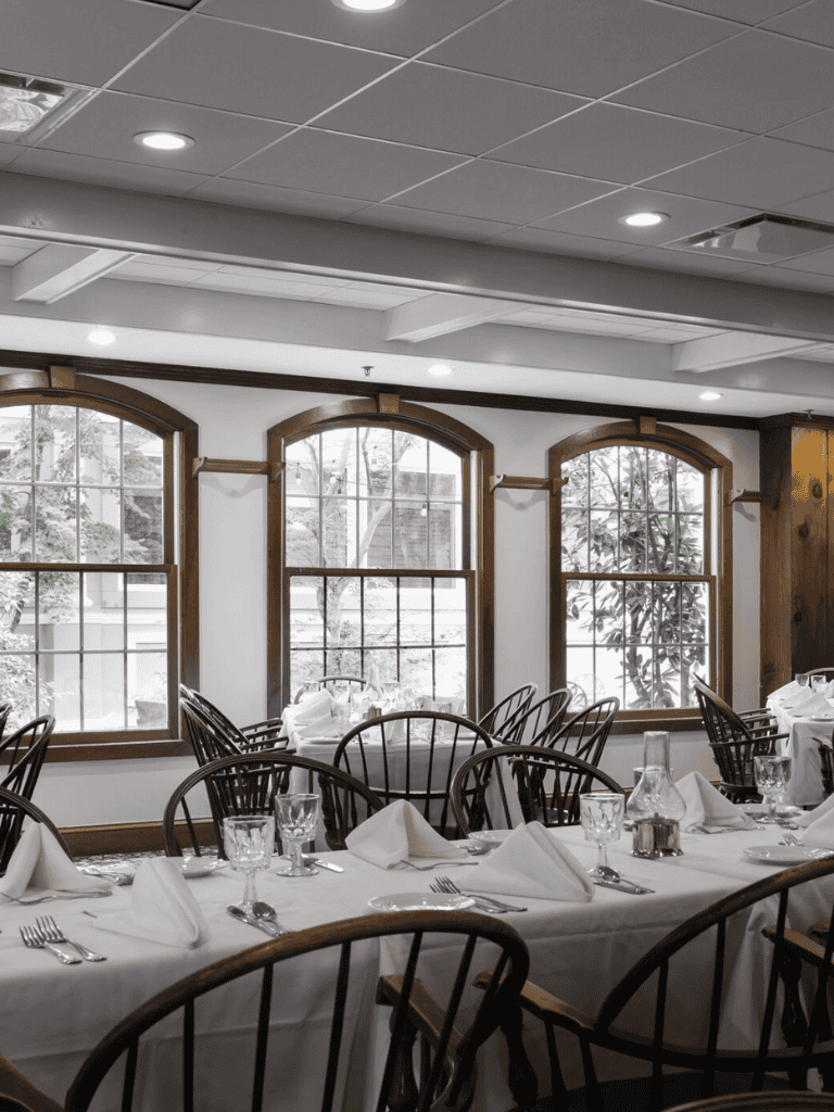 Elegant restaurant interior with white table settings and large arched windows, perfect for dining and special events.
