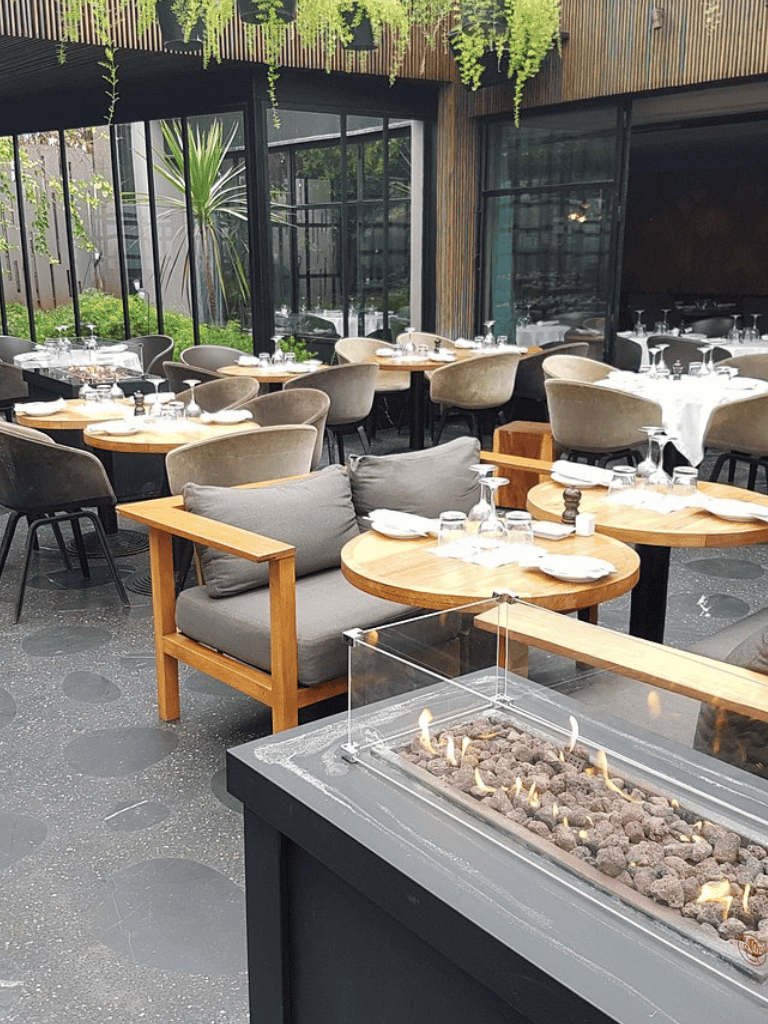 Relaxed modern restaurant with outdoor seating and fireplace, perfect for dining and social gatherings.