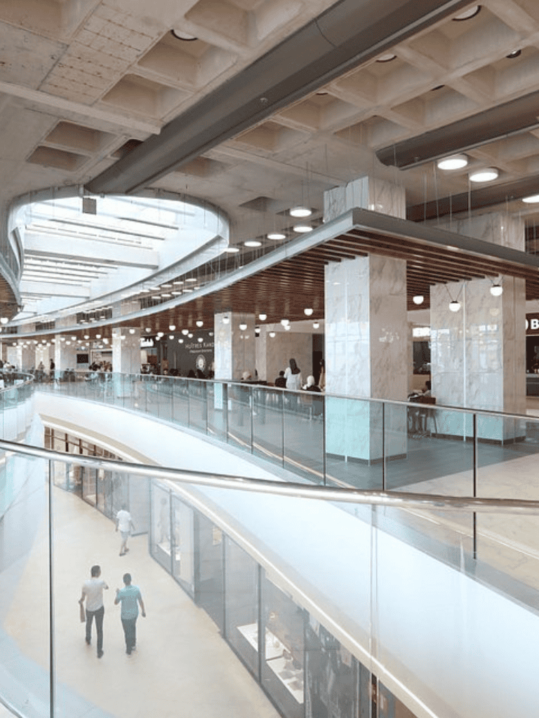 Bright modern shopping mall interior with multiple levels and glass railings, ideal for shopping and dining.