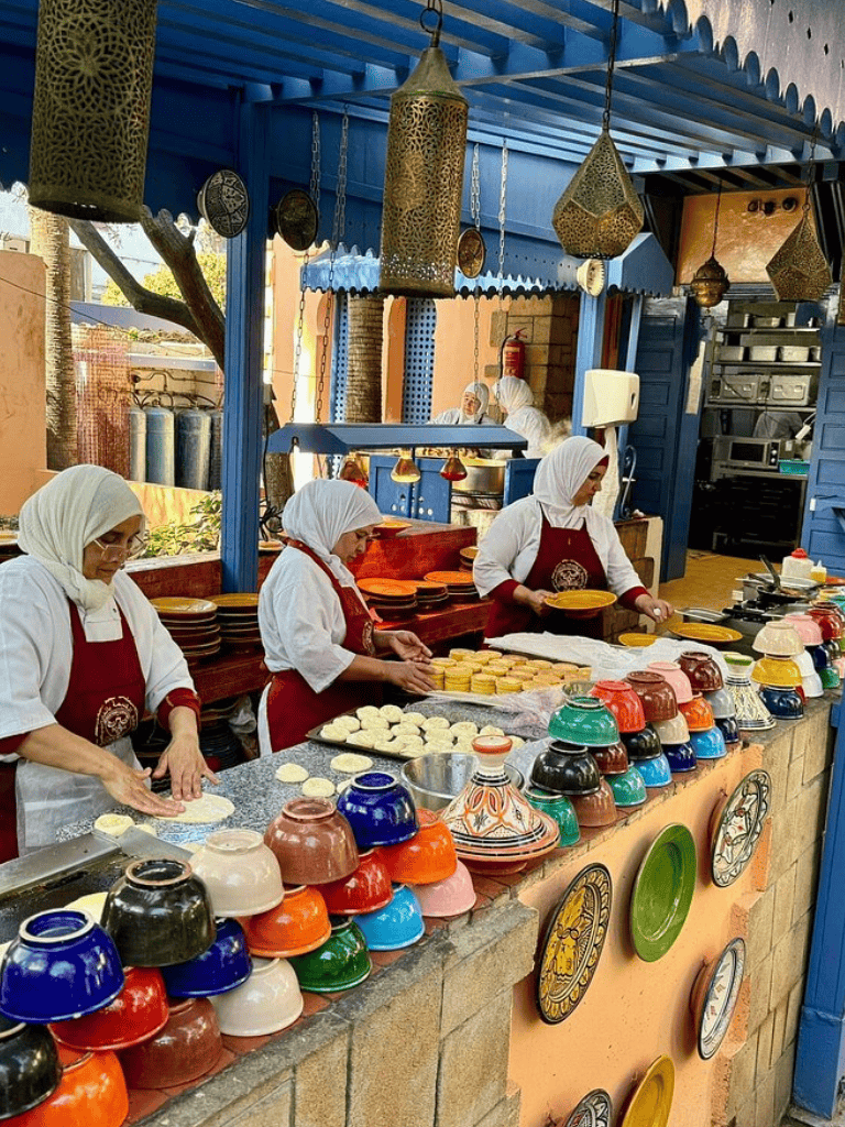 Colorful Moroccan kitchen with women preparing traditional dishes, vibrant decor, and cultural ambiance for an authentic culinary experience.