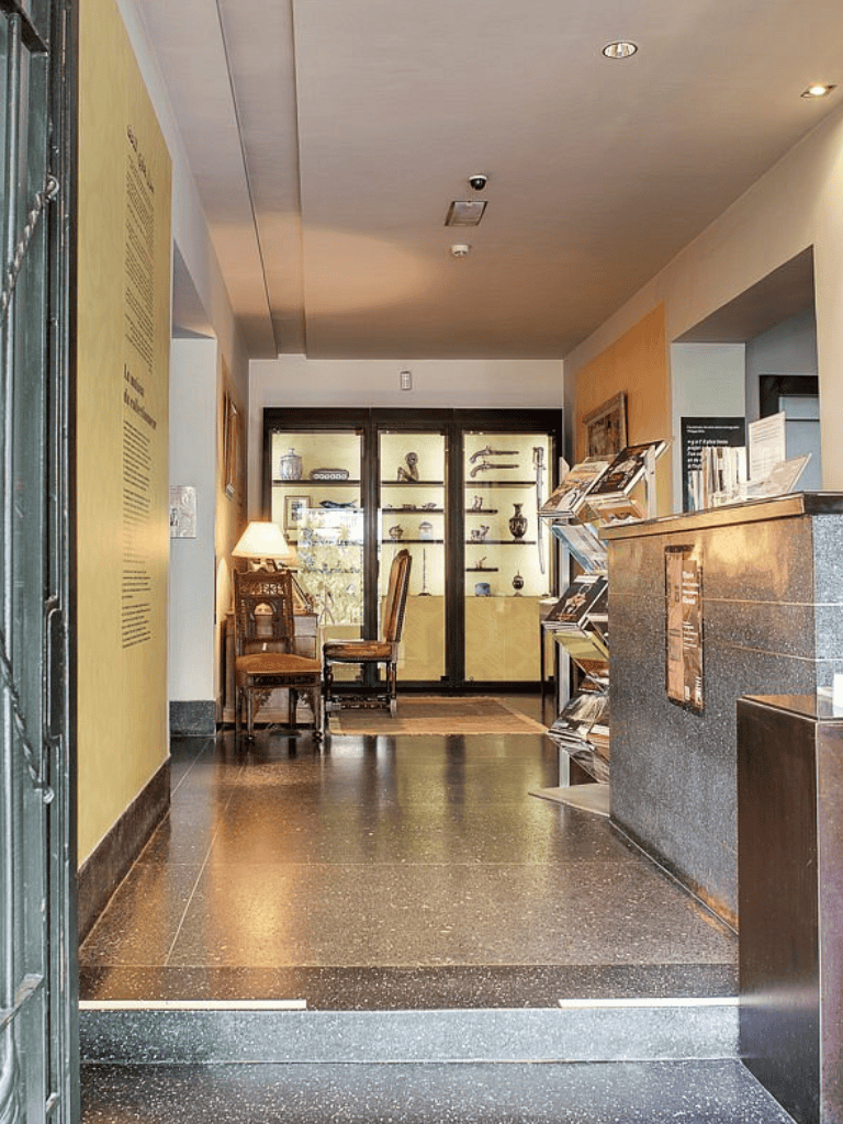 Vintage hotel lobby with antique chairs, display cabinet, and welcoming decor.