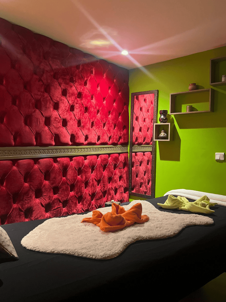 Colorful bedroom with red tufted headboard and green accent wall, offering a cozy ambiance for relaxation.