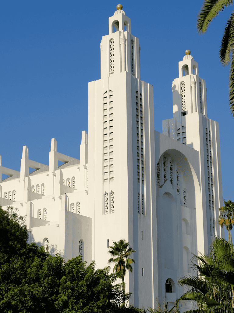 Majestic white mosque with tall minarets and intricate window designs against a clear blue sky.