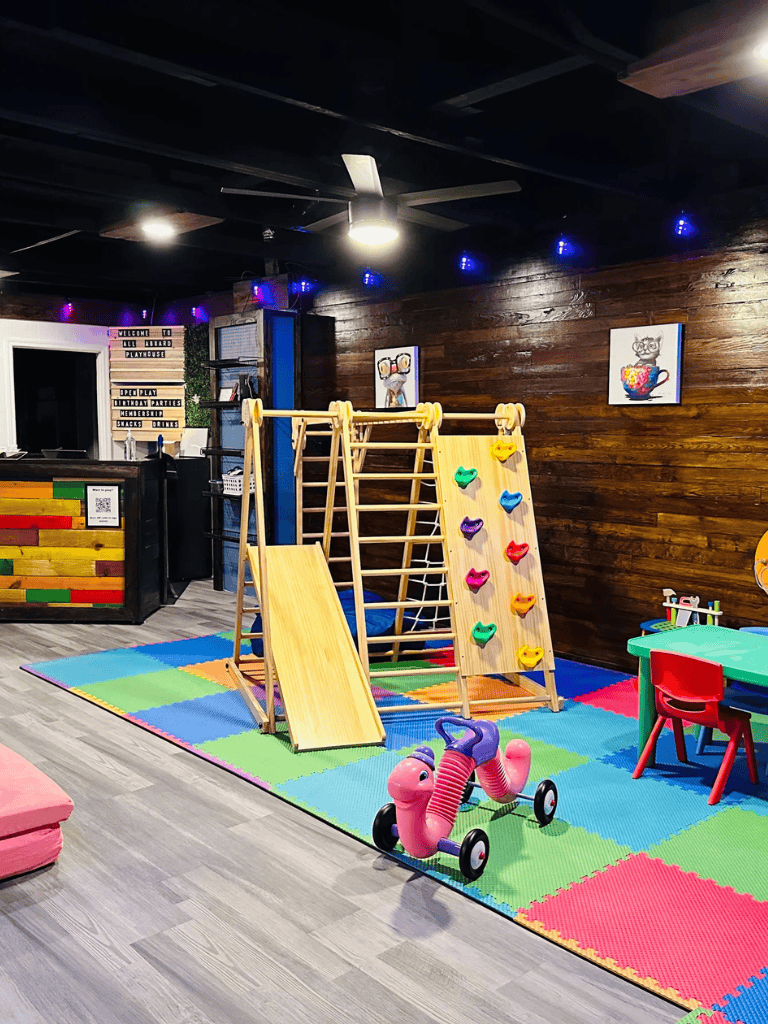 Colorful indoor children's play area with climbing wall and slide.