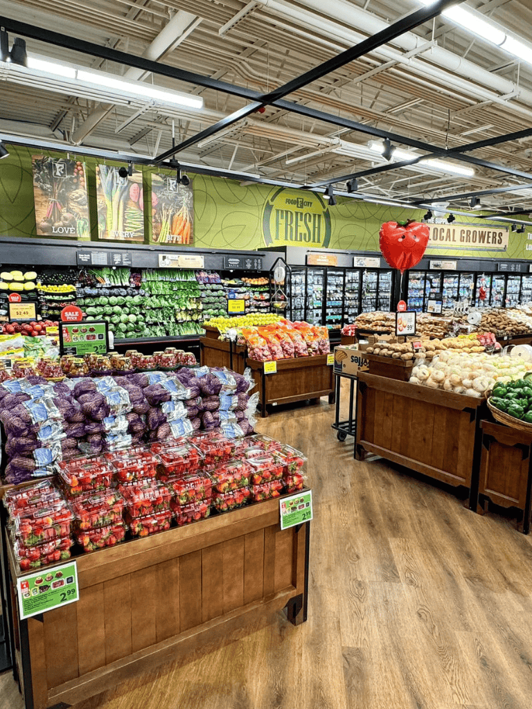 Fresh produce section at a grocery store, showcasing vegetables and fruits with signage—local growers and organic options available.