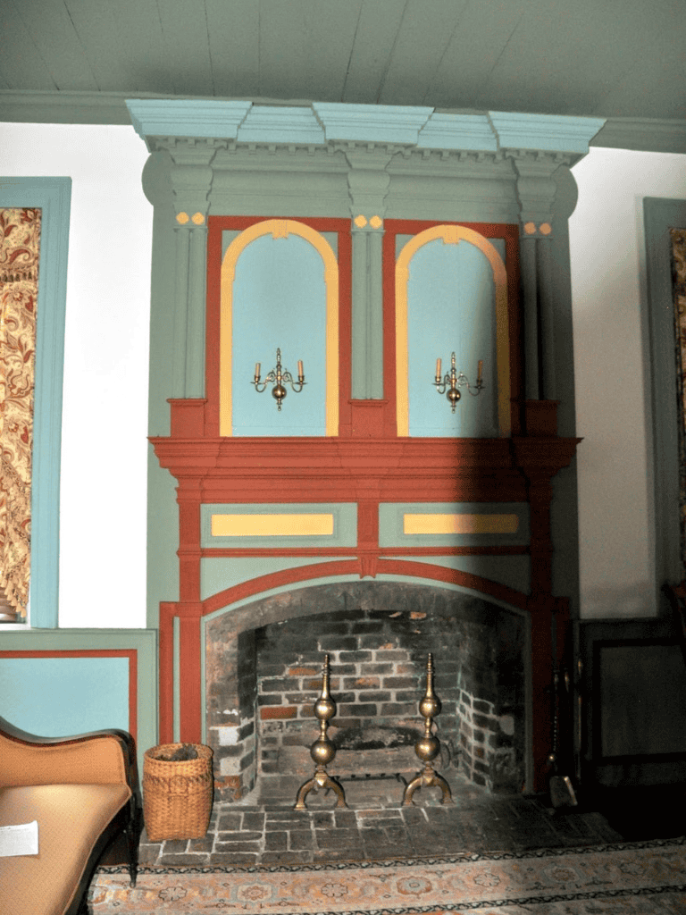Victorian-style painted fireplace with ornate woodwork and decorative lamps in a historic home.