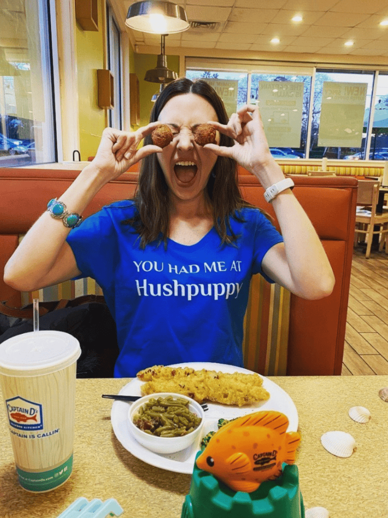 - Playful woman holding faux fried food items over her eyes at a casual restaurant.
