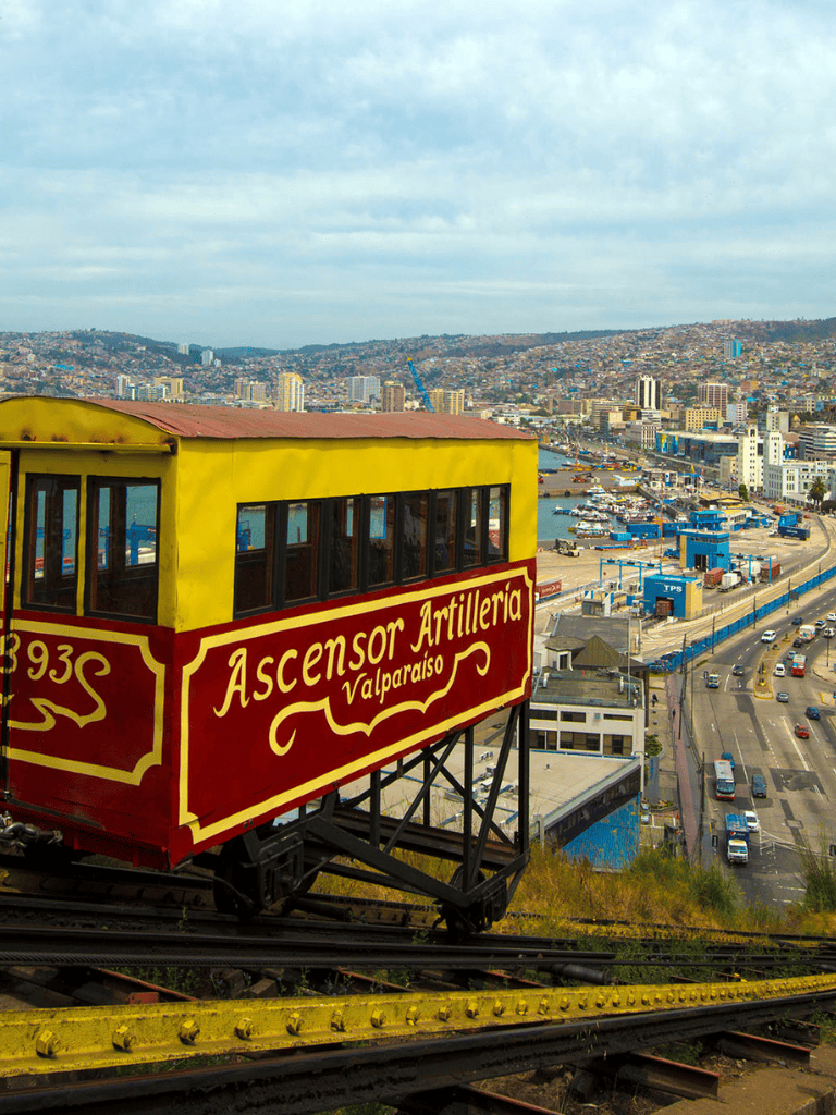 Vintage funicular railway car heading up the hillside in Valparaiso, Chile, offering scenic views of the city and harbor.