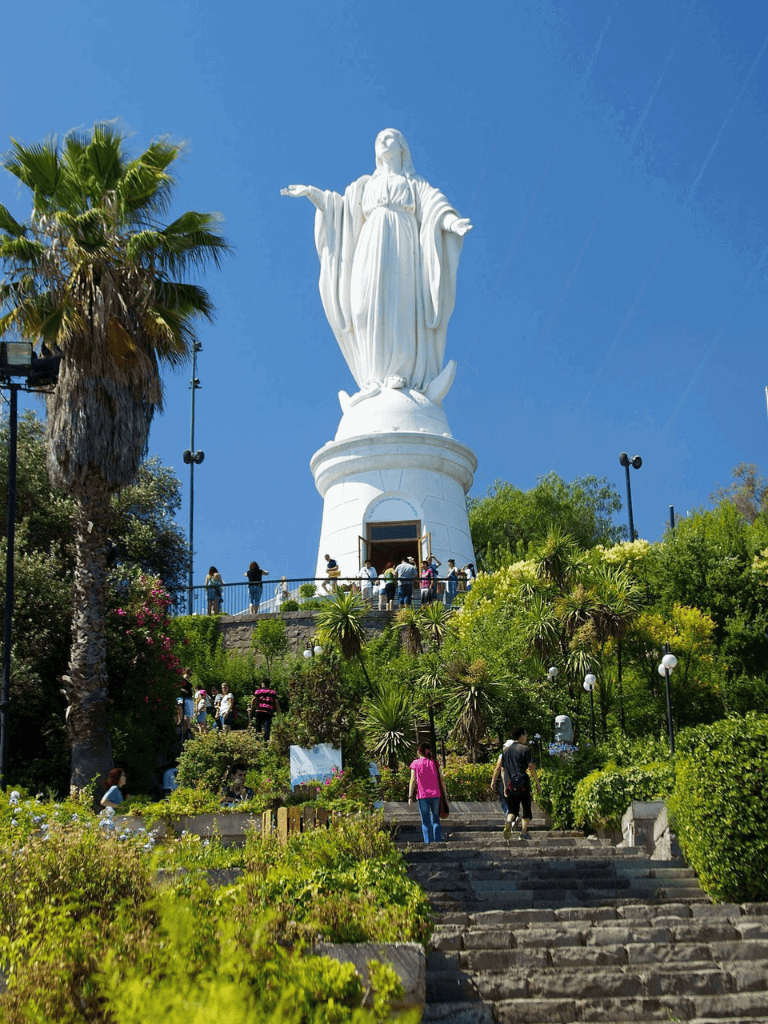 Tall Christ the Redeemer statue in Rio de Janeiro with lush greenery and visitors.