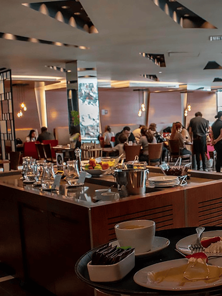 Elegant restaurant dining scene with people enjoying meals and a buffet setup.