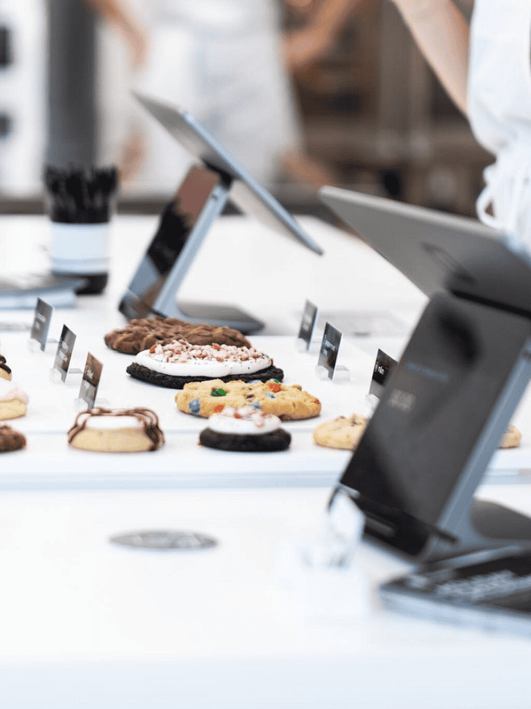 Delicious cookies on digital ordering kiosk at bakery, modern food service display.