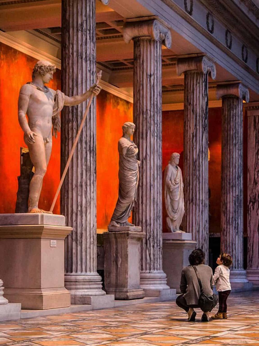 Ancient Greek statues in museum, children exploring classical sculptures, educational cultural visit, museum art and history.