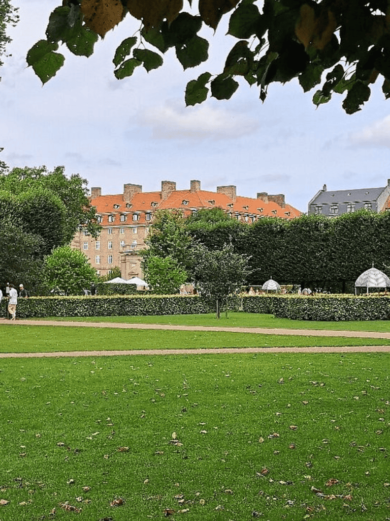 A lush green park with historic buildings and trees, perfect for outdoor activities and sightseeing in a city setting.
