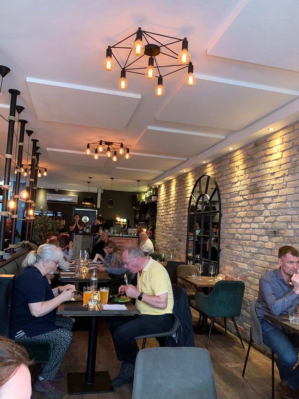 Modern restaurant interior with exposed brick wall and stylish lighting fixtures.