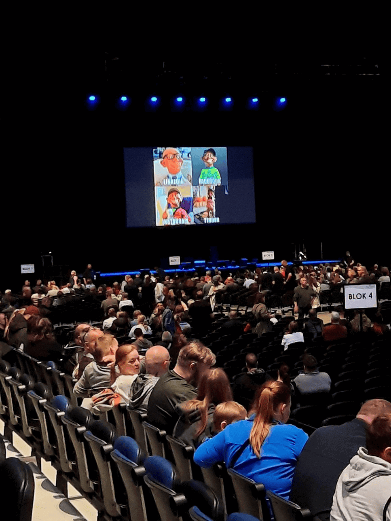 1. Audience watching a live presentation on stage at QuestForDirections event.