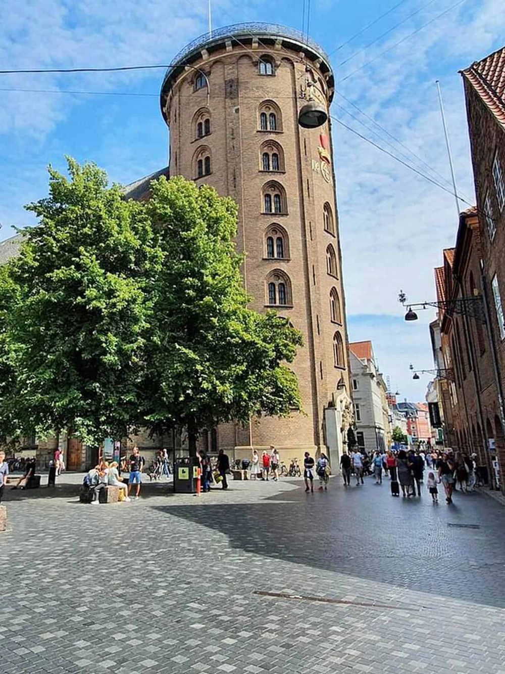 Historic city tower in Copenhagen, Denmark, with bustling street scene and vibrant community atmosphere.