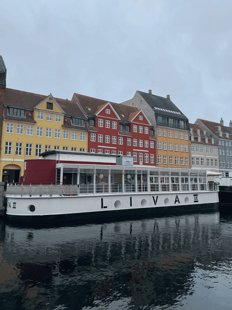 Colorful historic buildings on the waterfront with a boat named LOI VACA II in Copenhagen, Denmark.