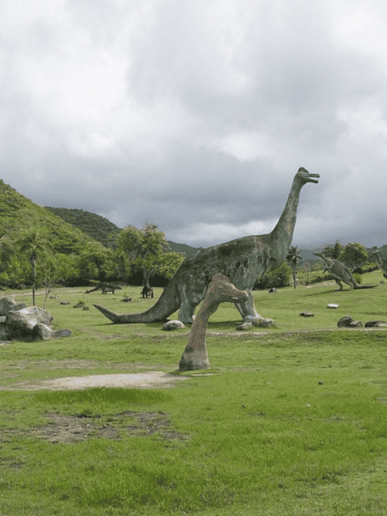 Dinosaur park with life-sized fossil replicas and lush green landscape, ideal for family fun and educational visits.