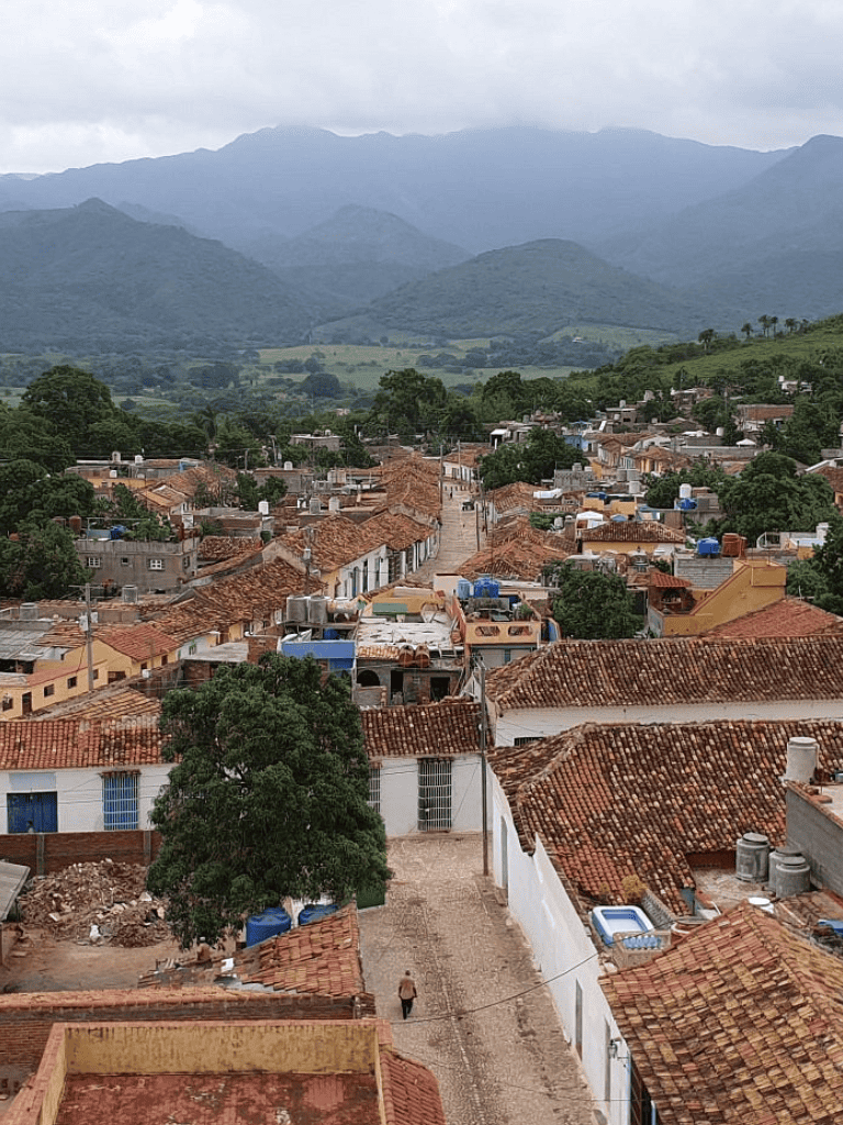 Historic town with traditional tiled roofs amidst lush green mountains, showcasing local architecture and scenic landscapes.