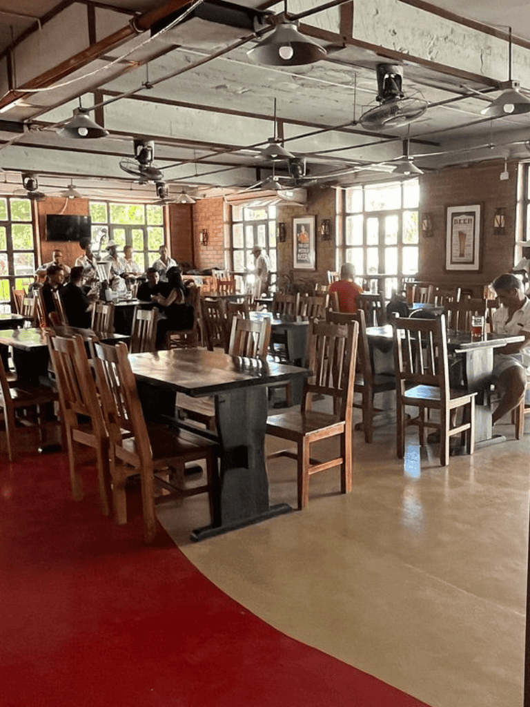 Aerial view of a cozy, rustic restaurant with wooden chairs and tables, exposed brick walls, and large windows letting in natural light.