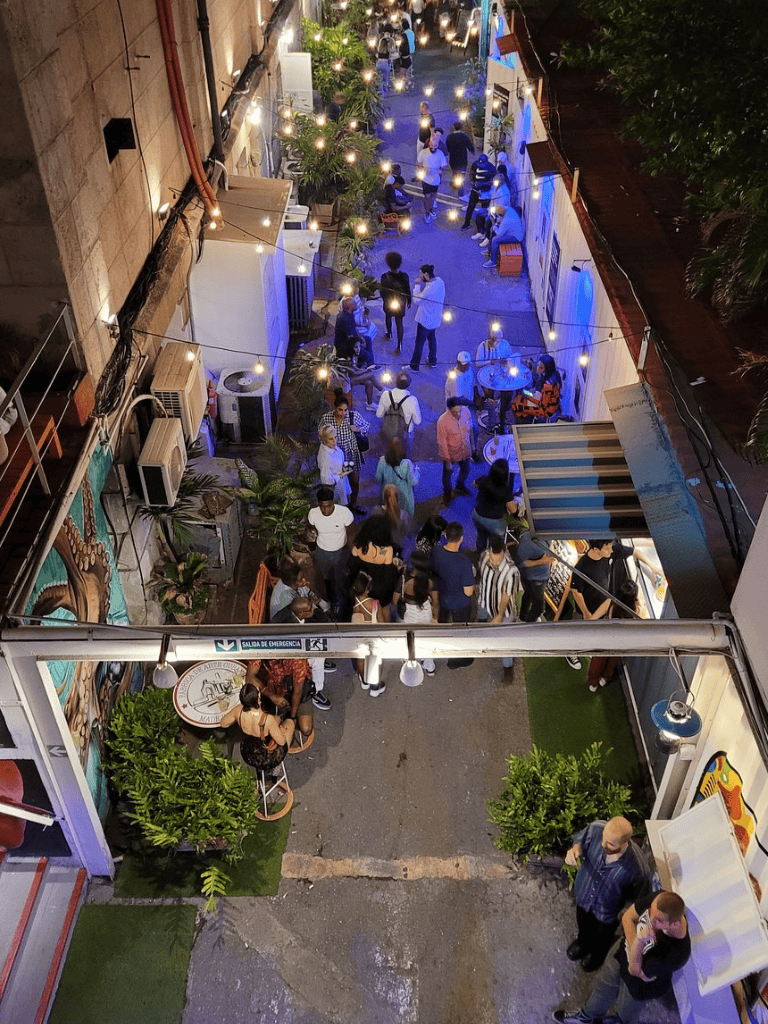 Vibrant outdoor nightlife scene at QuestForDirections restaurant with colorful lighting and lively crowd.