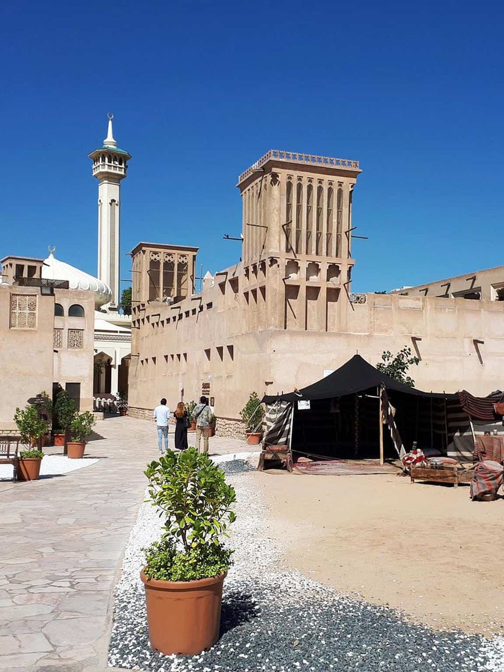 Ancient Middle Eastern fortress with high walls, minaret, and tents, showcasing Middle Eastern architecture.
