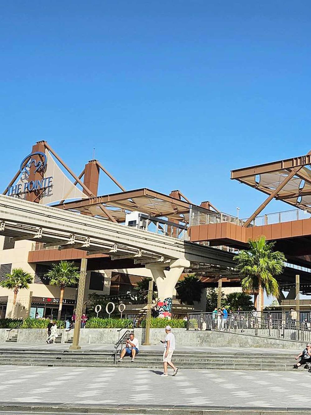 Vibrant outdoor scene at The Pointe in Orlando, featuring shopping, dining, and entertainment under a clear blue sky.