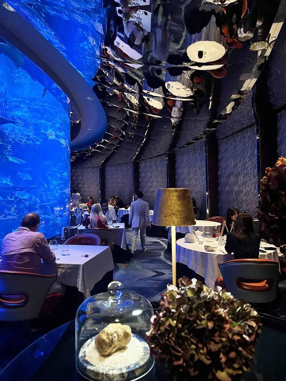 Elegant underwater-themed restaurant with vibrant blue lighting and modern decor.