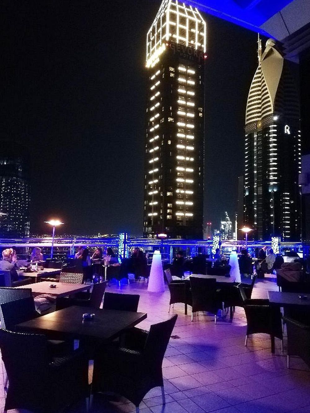 Cityscape view of a modern rooftop restaurant with illuminated skyscrapers at night, perfect for travel and dining in urban settings.