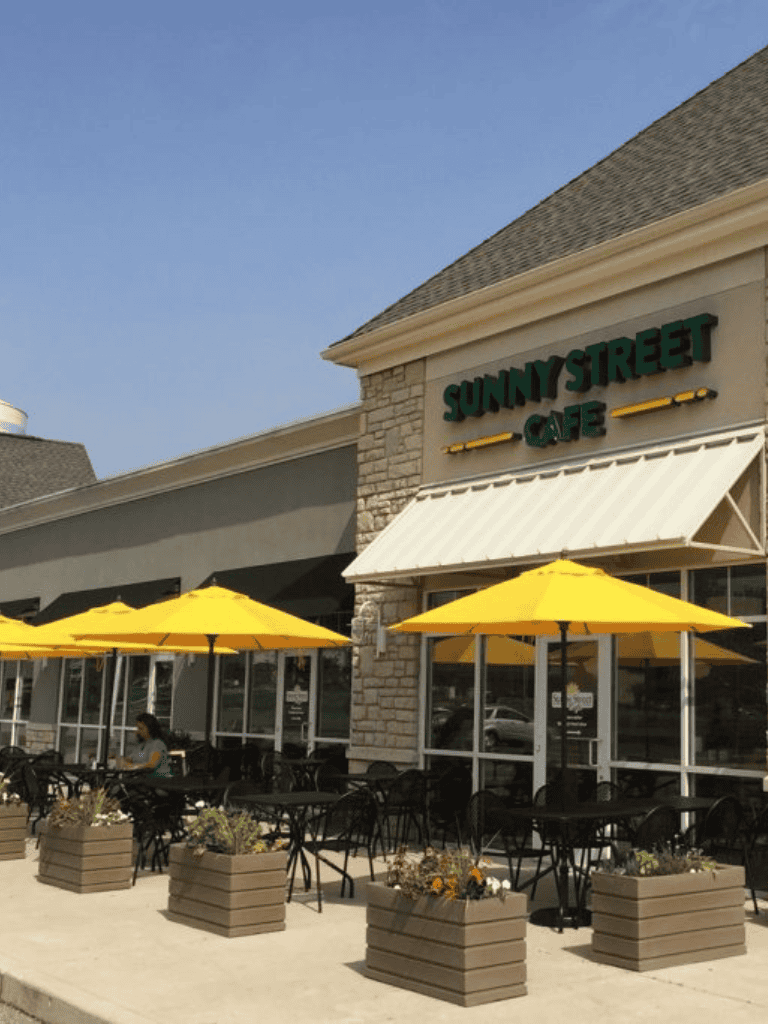 Sunny Street Cafe outdoor seating with yellow umbrellas, inviting atmosphere for breakfast or coffee.