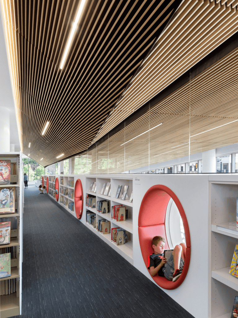 Bright modern library interior with unique circular reading nooks for kids and contemporary wooden ceiling design for quest for directions.