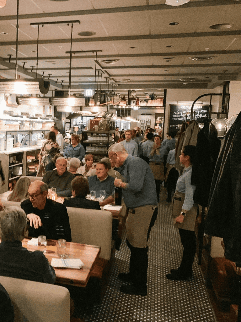 Cozy restaurant interior with patrons dining and staff serving, perfect for exploring dining options with Quest For Directions.