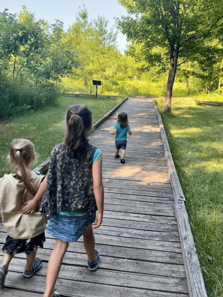 Kids walking on a wooden trail in a lush green park for outdoor adventure.
