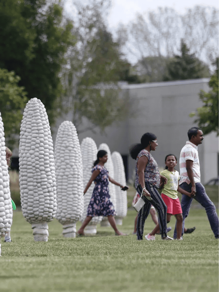 Colorful outdoor sculpture park with family visitors exploring modern art installations.