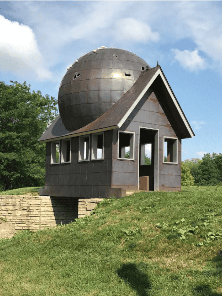 Unique planetarium house with spherical observatory on rooftop, eco-friendly design, surrounded by greenery.