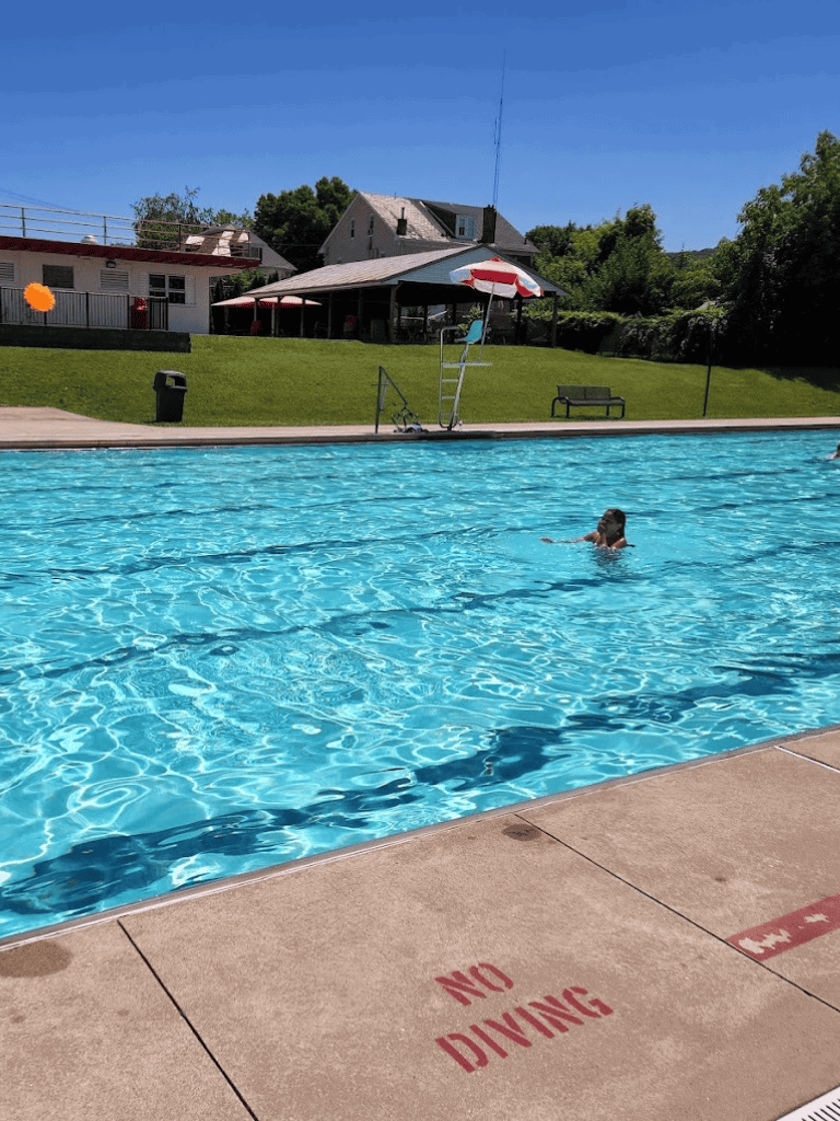 Swimming pool with clear water and a child swimming, outdoor recreational area, QuestForDirections.