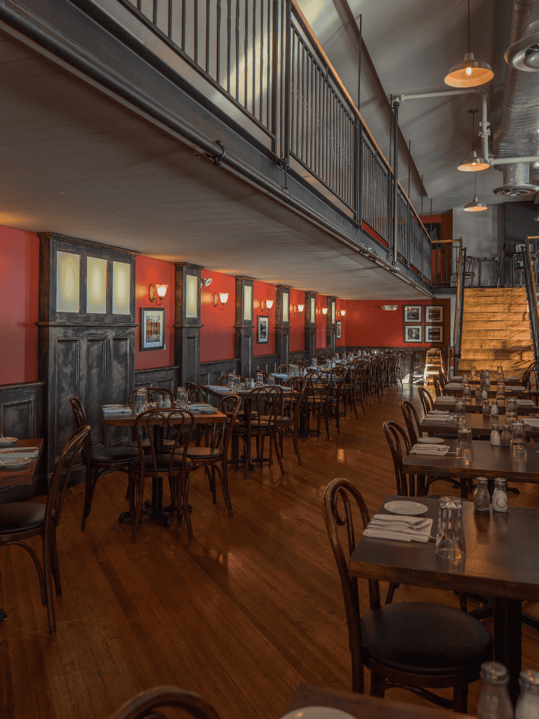 Broad, stylish restaurant interior with wooden floors, red walls, and elegant lighting, perfect for dining and events.