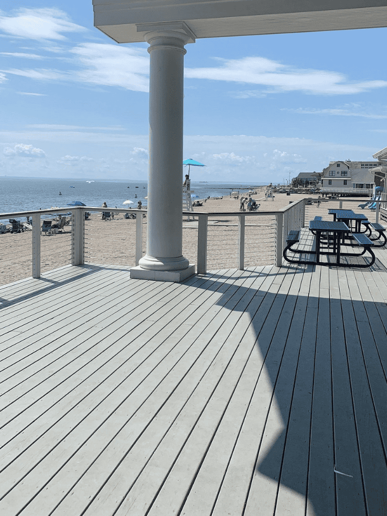 Relaxing beach view from a coastal boardwalk with seating and umbrellas, perfect for seaside relaxation.