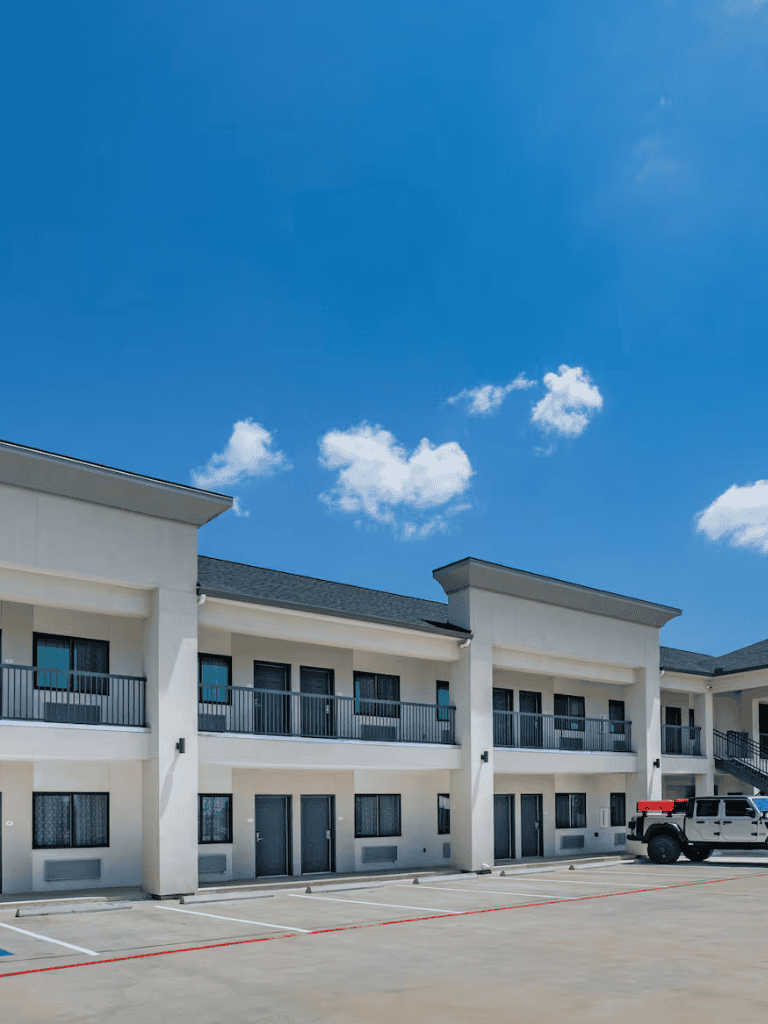 Modern hotel exterior with parking lot under blue sky.