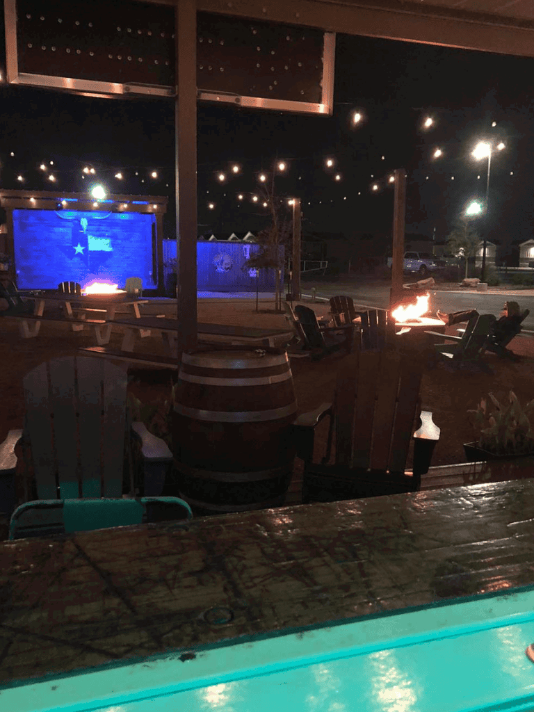 Texas-themed outdoor venue with fire pits, string lights, and a large screen for events and gatherings.