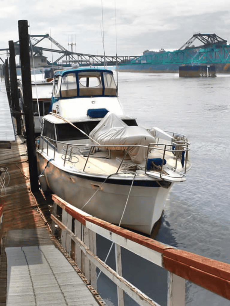 Docked yacht at waterfront marina with bridge in background, scenic boating destination.