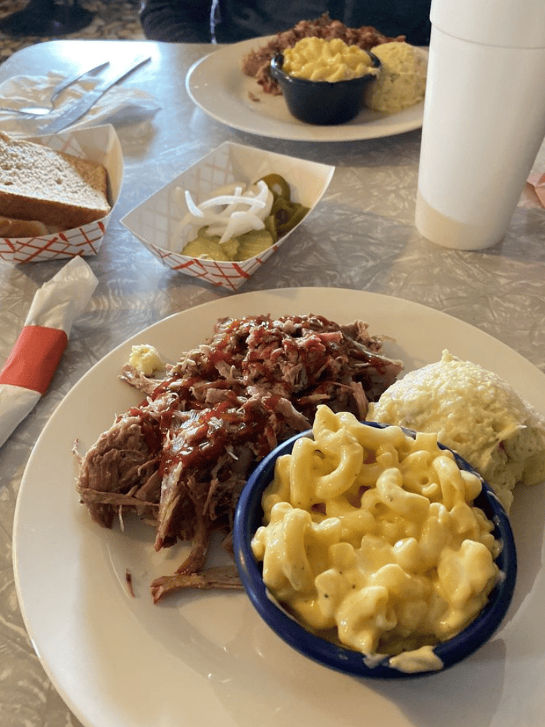 Juicy barbecue ribs with macaroni and cheese and mashed potatoes on a white plate.