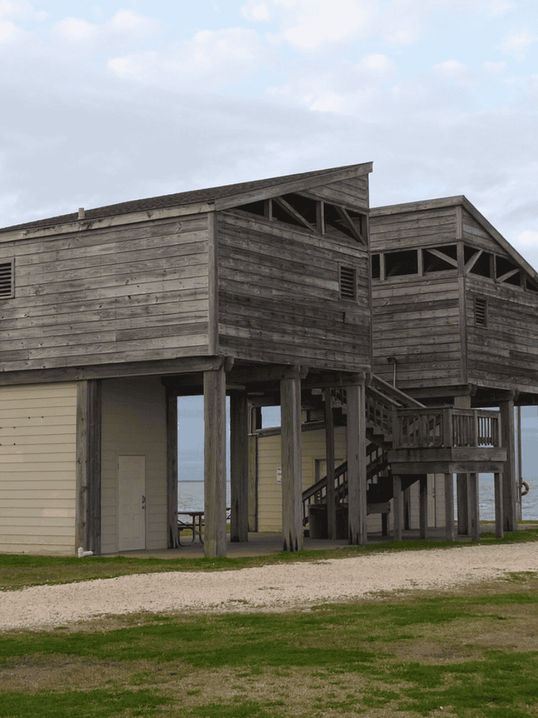 Weathered beachfront wooden cabin with stairs and ocean view, ideal for coastal vacation stays.