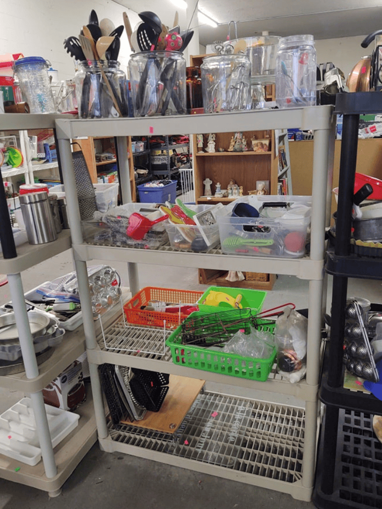 1. Assorted kitchen utensils and cookware on a metal cart in a thrift store.