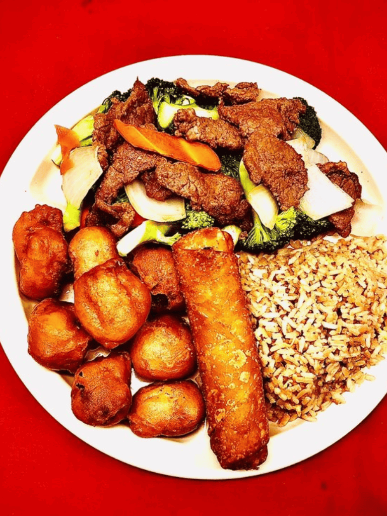 Crispy spring rolls and fried plantains served with stir-fried beef and vegetables on a white plate.