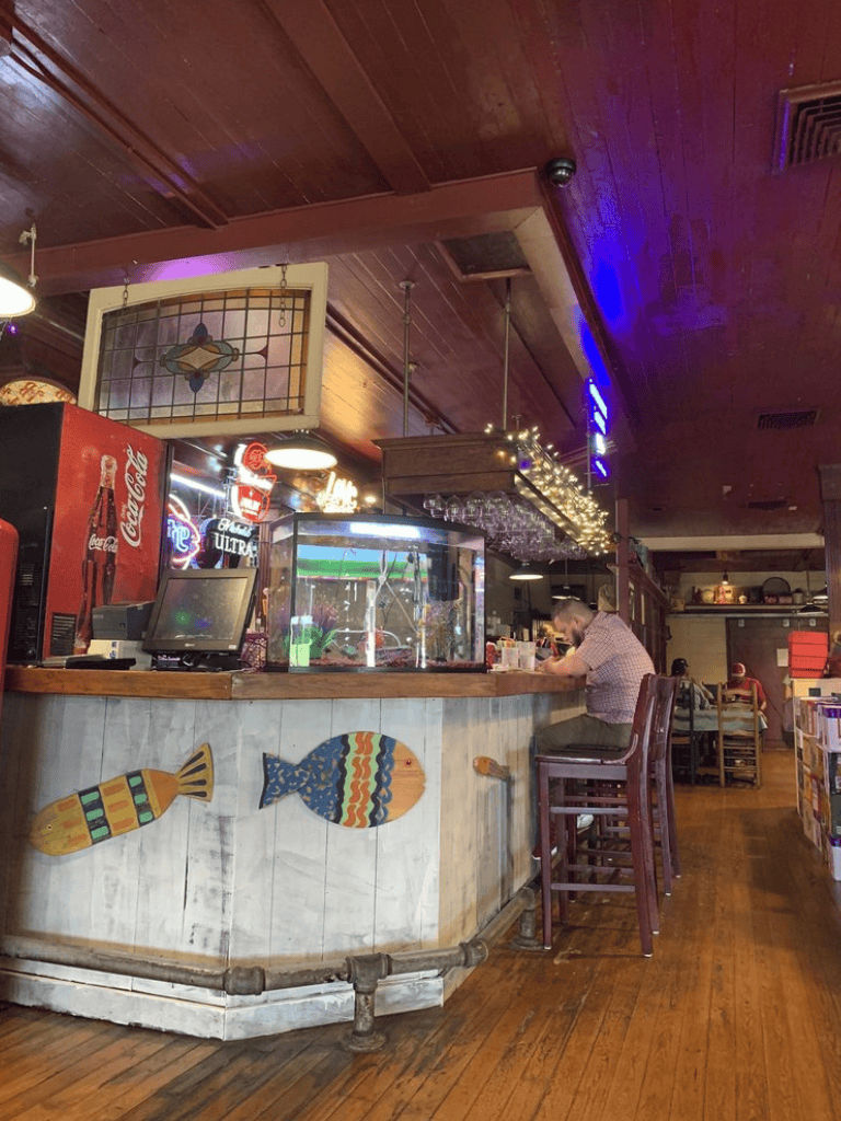 Cozy bar with wooden decor, serving drinks with nautical fish decorations and a seafood-themed ambiance.