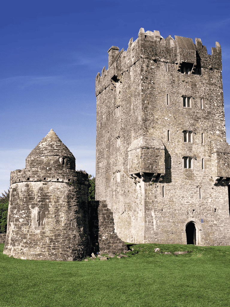 Ancient stone castle with turrets and battlements in scenic green landscape, historical Irish fortress.
