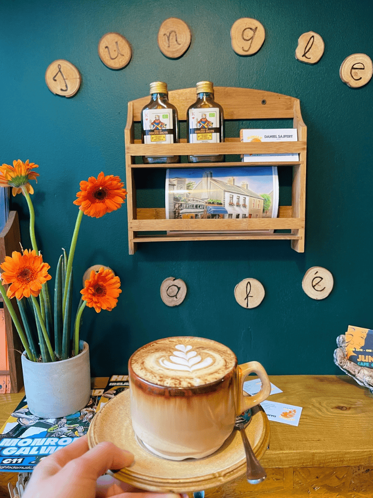 Coffee with latte art in a cozy café setting with a blue wall, decorative wooden letters, and a vibrant flower arrangement.