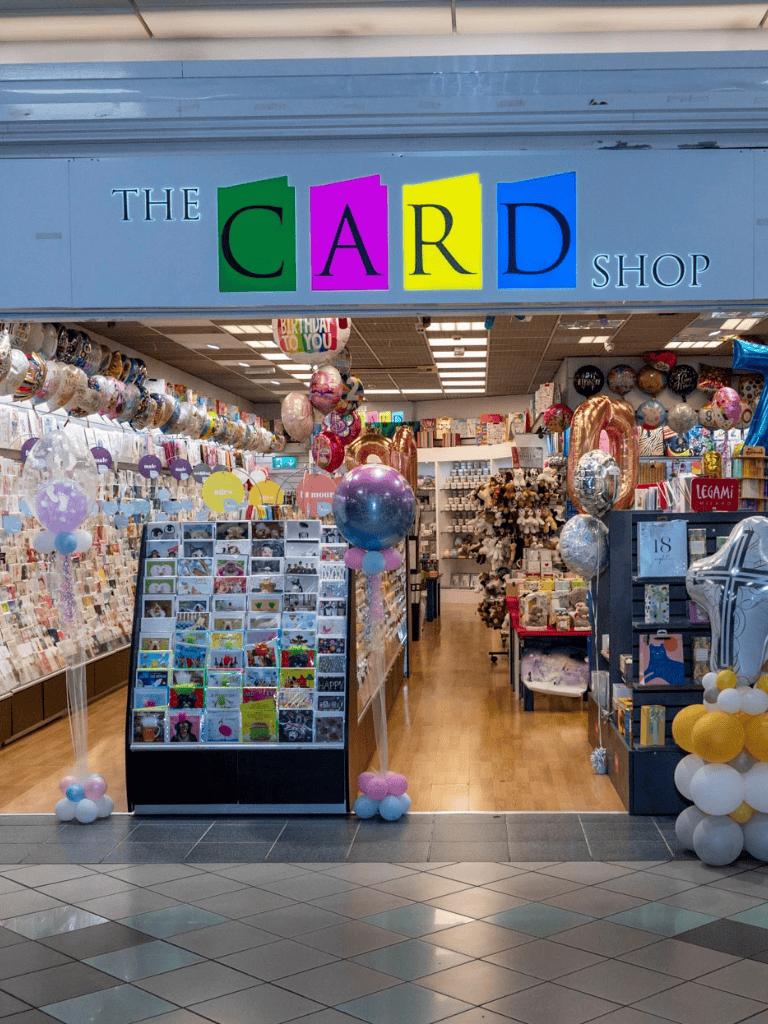 Bright gift card and balloon shop inside a mall, vibrant store entrance, ideal for gift shopping.