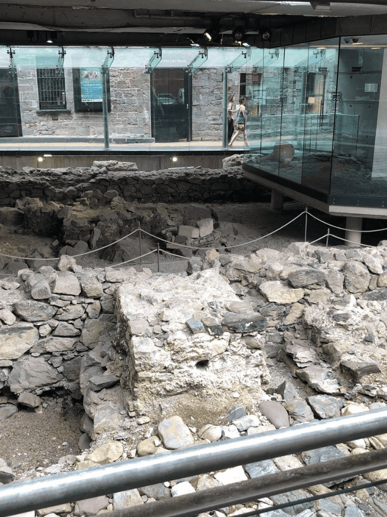 Ancient archaeological site with stone ruins inside a modern museum exhibit.